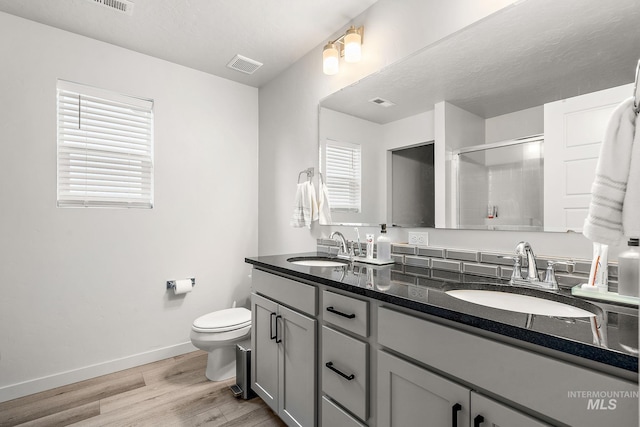 bathroom featuring toilet, vanity, a shower with shower door, and hardwood / wood-style floors