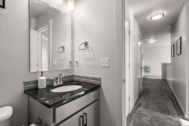 bathroom with toilet, a textured ceiling, and vanity