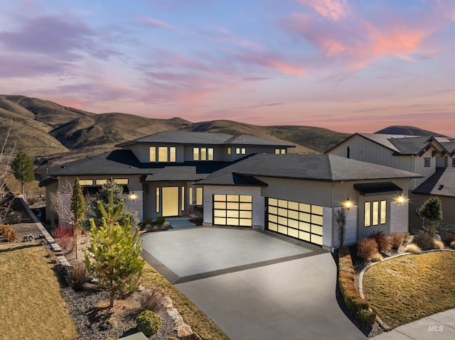 prairie-style house with driveway, a shingled roof, an attached garage, and a mountain view