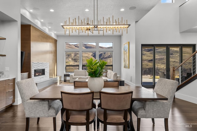 dining space featuring a textured ceiling, dark wood-type flooring, a tiled fireplace, and baseboards