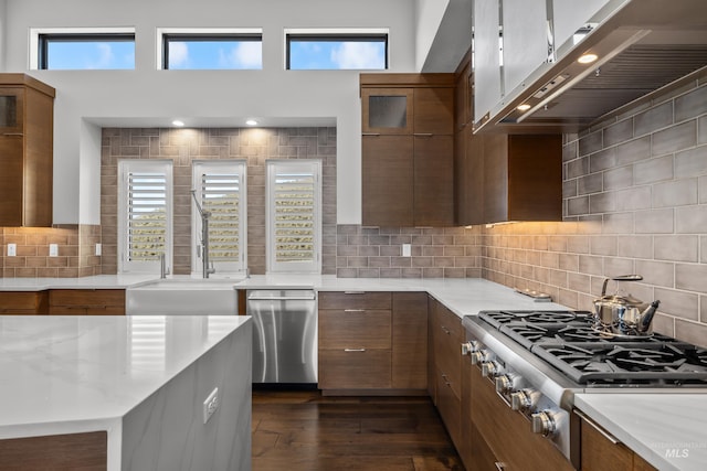 kitchen featuring a healthy amount of sunlight, brown cabinetry, stainless steel appliances, and dark wood-style flooring