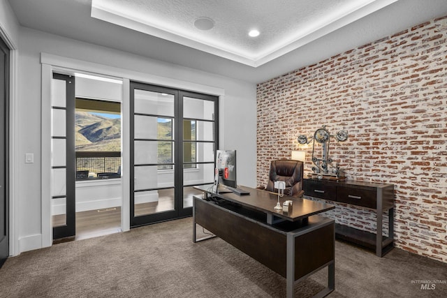 office area with dark colored carpet, french doors, a textured ceiling, and brick wall