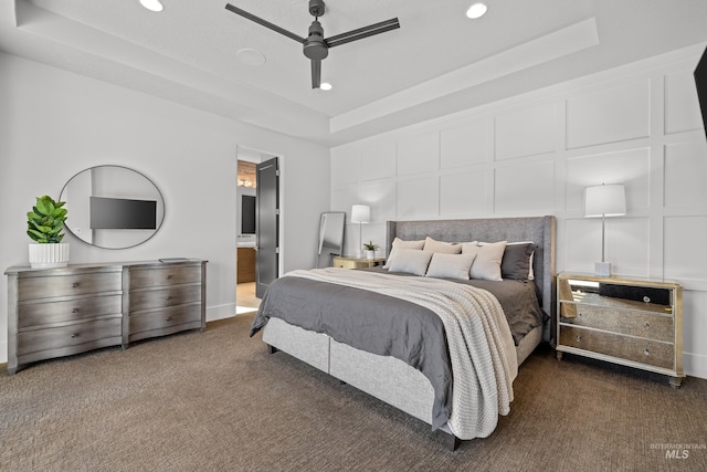 carpeted bedroom with ceiling fan, connected bathroom, recessed lighting, a decorative wall, and a raised ceiling