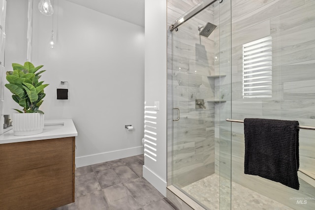 full bathroom featuring a stall shower, baseboards, and vanity