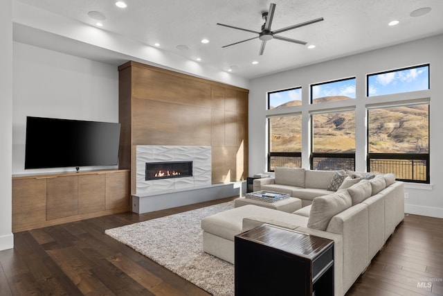 living area featuring recessed lighting, dark wood-style flooring, and a large fireplace