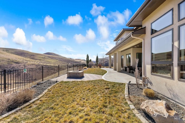 view of yard featuring a fire pit, a patio area, a fenced backyard, and a mountain view