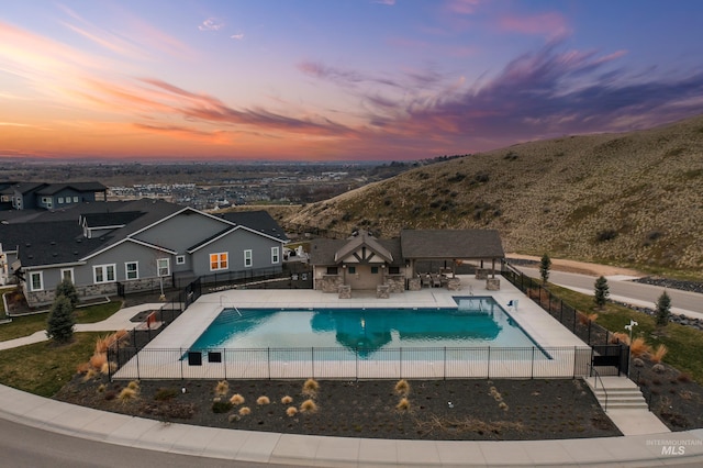 pool at dusk featuring a fenced in pool, fence, and a patio