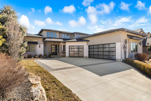 prairie-style home with an attached garage, driveway, and stucco siding