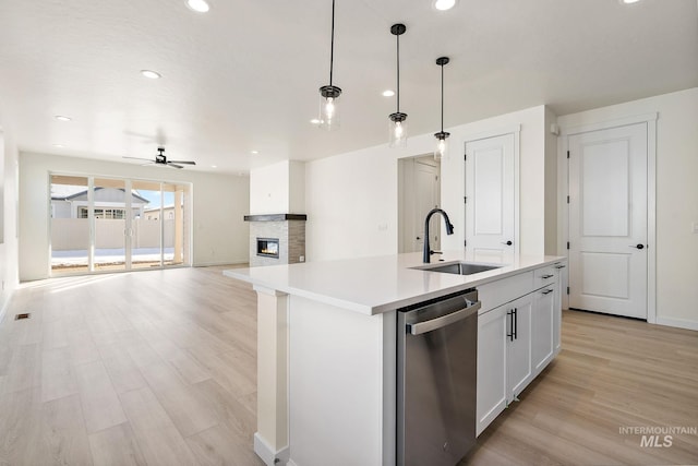 kitchen with decorative light fixtures, light countertops, stainless steel dishwasher, open floor plan, and a sink