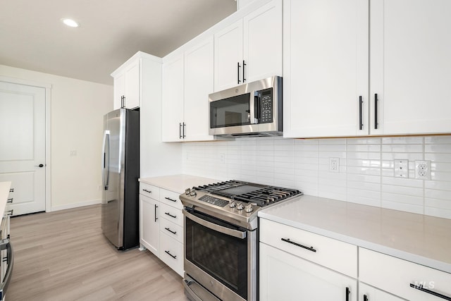 kitchen featuring light wood-style floors, white cabinets, light countertops, appliances with stainless steel finishes, and decorative backsplash