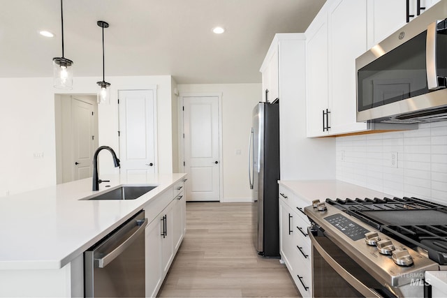 kitchen featuring stainless steel appliances, a sink, white cabinetry, hanging light fixtures, and light countertops