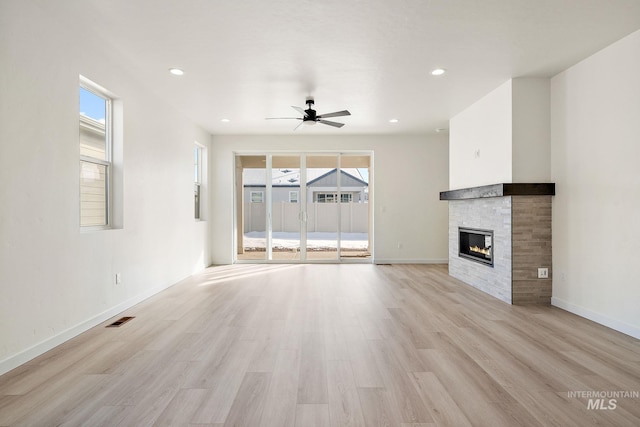 unfurnished living room featuring a ceiling fan, a glass covered fireplace, visible vents, and light wood-style floors