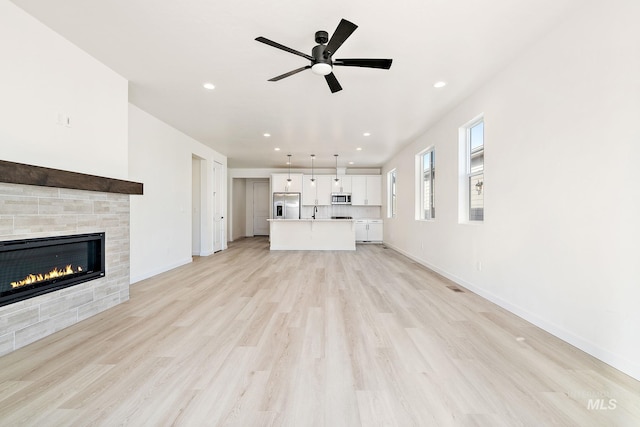 unfurnished living room with light wood-style floors, recessed lighting, and a tile fireplace