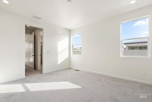 unfurnished room with light carpet, recessed lighting, visible vents, and baseboards