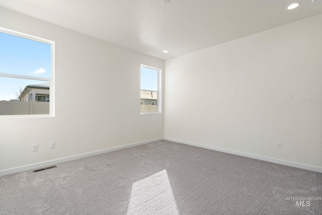 carpeted spare room featuring baseboards, visible vents, and recessed lighting