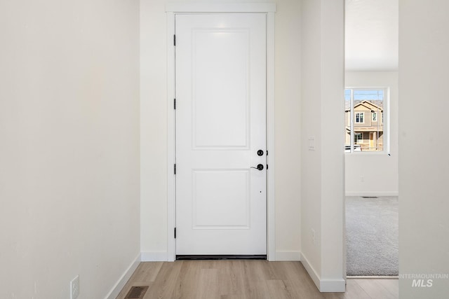 doorway to outside featuring baseboards, visible vents, and light wood-style floors