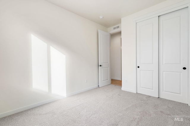 unfurnished bedroom with baseboards, a closet, visible vents, and light colored carpet