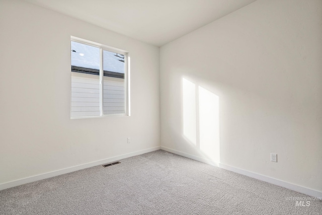 spare room with carpet floors, baseboards, and visible vents