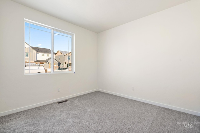 carpeted empty room with visible vents and baseboards