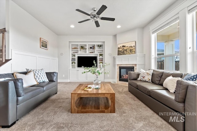 carpeted living room with built in features and ceiling fan