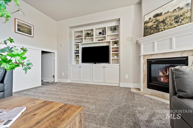 carpeted living room featuring built in features and a tile fireplace