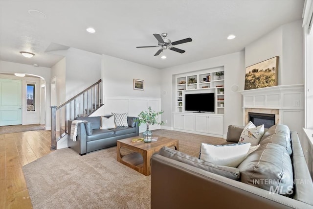 living room with ceiling fan, light hardwood / wood-style floors, and built in shelves