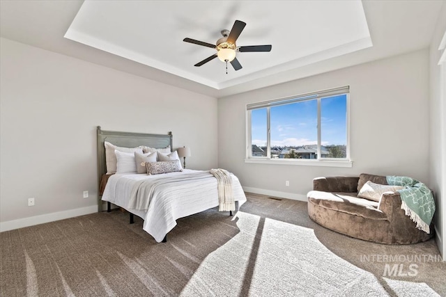 bedroom featuring a raised ceiling, ceiling fan, and carpet flooring