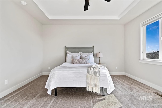 bedroom with a raised ceiling, carpet, and ceiling fan