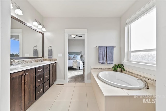 bathroom featuring a relaxing tiled tub, vanity, and tile patterned flooring