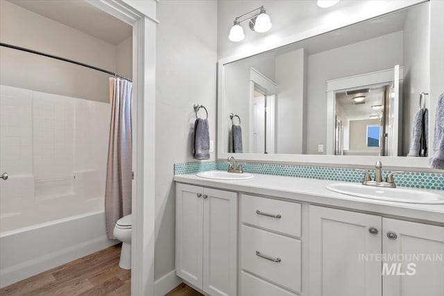 full bathroom with shower / bath combo, vanity, wood-type flooring, and toilet