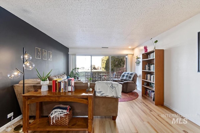 home office with light wood finished floors, baseboards, and a textured ceiling