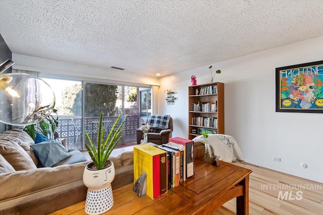 living room featuring a textured ceiling, baseboards, and wood finished floors