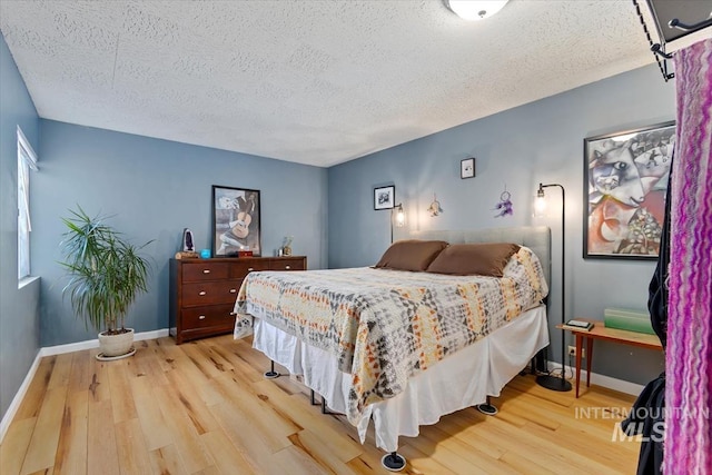 bedroom with a textured ceiling, light wood finished floors, and baseboards