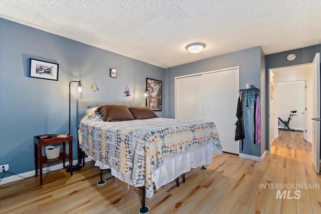 bedroom with a closet, baseboards, and light wood finished floors