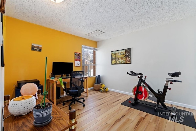 home office with a textured ceiling, wood finished floors, and baseboards