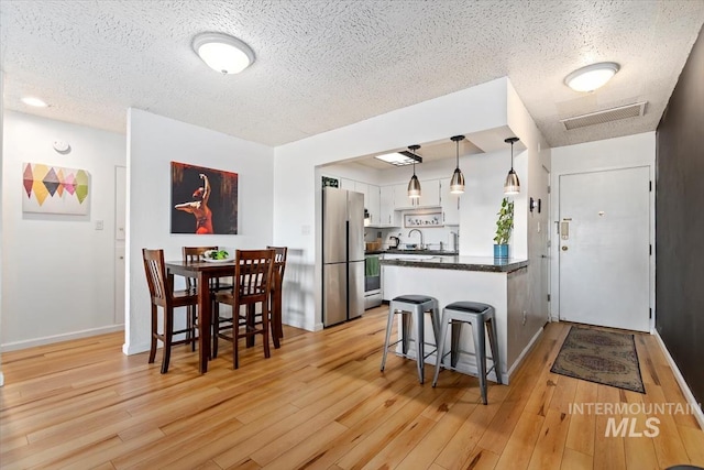 kitchen featuring stainless steel appliances, a peninsula, visible vents, white cabinetry, and dark countertops