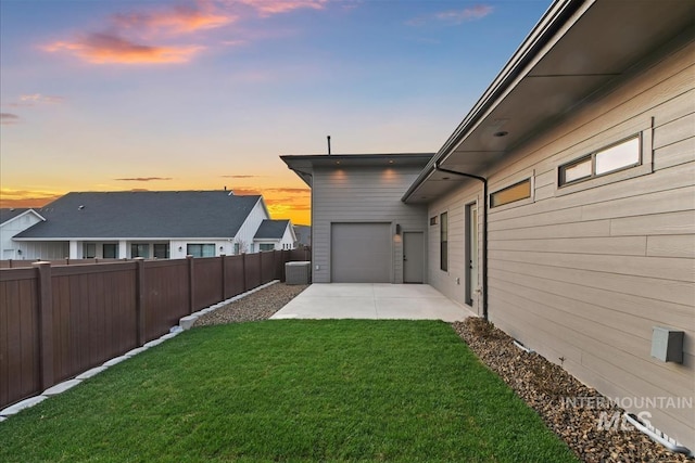 9891 W Napier Ct, Star, ID 83669 - yard at dusk with an attached garage, a fenced backyard, a patio, and concrete driveway