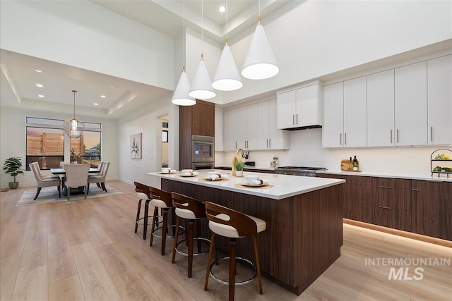 9891 W Napier Ct, Star, ID 83669 - kitchen with a raised ceiling, light wood finished floors, a breakfast bar, white cabinets, and a kitchen island
