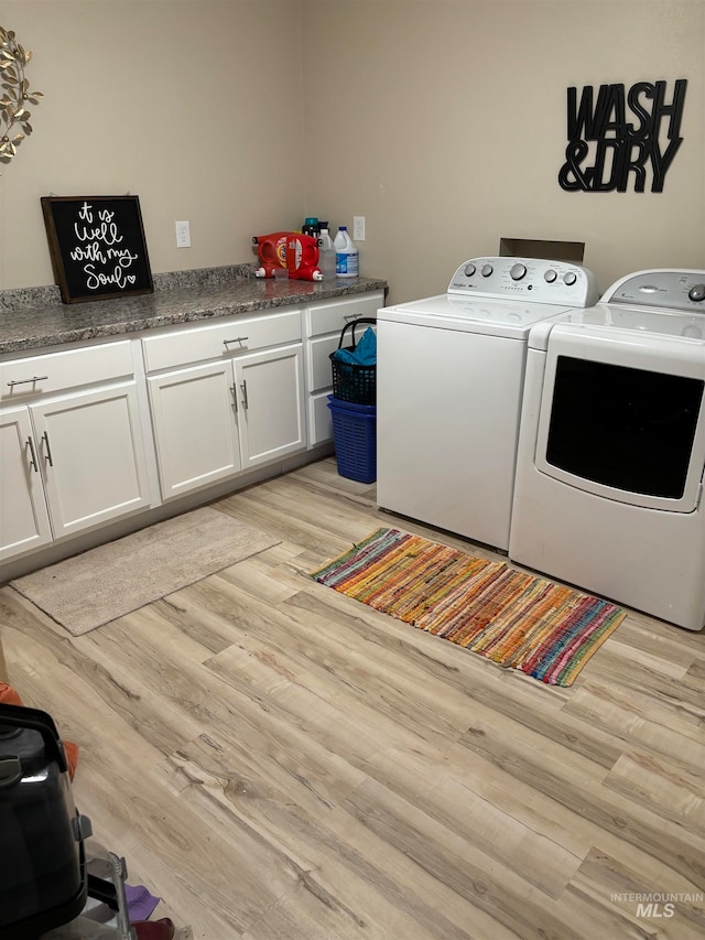 laundry room featuring cabinets, light wood-type flooring, and washer and clothes dryer