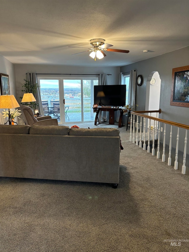 carpeted living room featuring a textured ceiling and ceiling fan