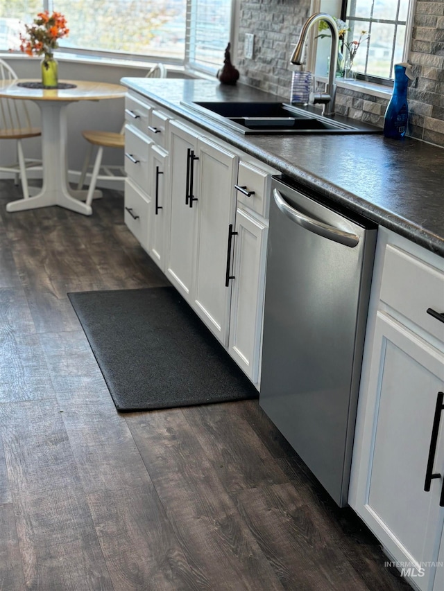 kitchen with stainless steel dishwasher, sink, white cabinets, and dark wood-type flooring