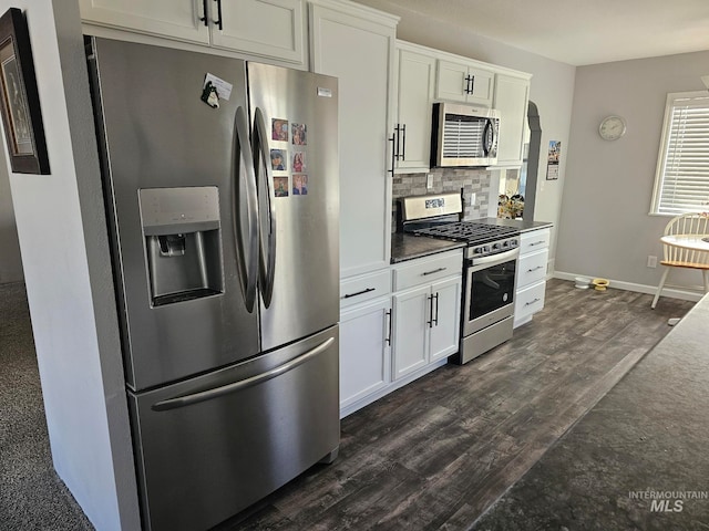 kitchen with appliances with stainless steel finishes, dark hardwood / wood-style flooring, white cabinetry, and backsplash