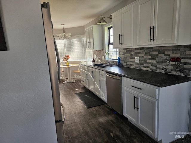 kitchen featuring dark wood-type flooring, white cabinets, sink, appliances with stainless steel finishes, and tasteful backsplash