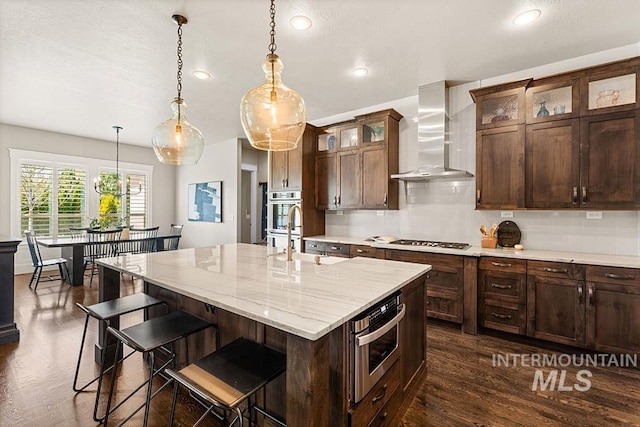 3061 S Fox Run Ave, Eagle, ID 83616 - kitchen featuring wall chimney range hood, a sink, stainless steel appliances, tasteful backsplash, and hanging light fixtures