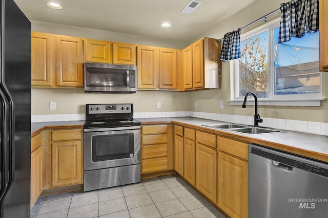 kitchen with sink, light tile patterned floors, and appliances with stainless steel finishes