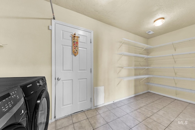 laundry room with washer and dryer, light tile patterned floors, and a textured ceiling