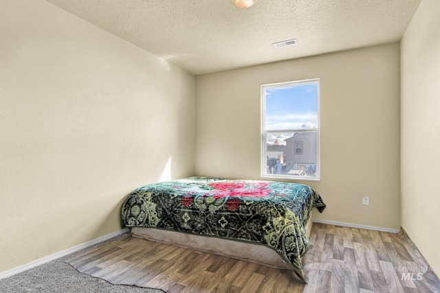 bedroom featuring a textured ceiling and hardwood / wood-style flooring