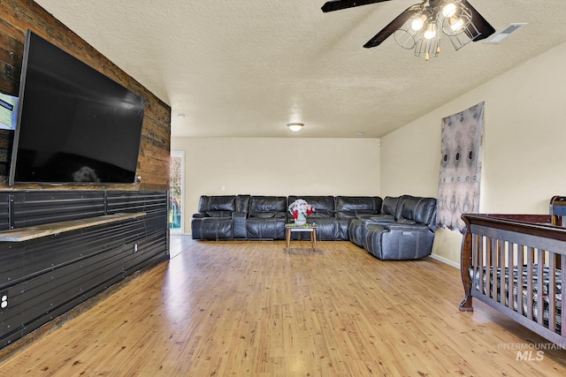 living room with ceiling fan, light hardwood / wood-style floors, and a textured ceiling