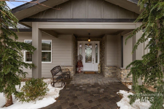 view of exterior entry featuring stone siding and board and batten siding