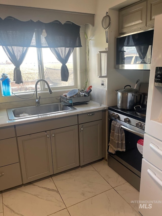 273 N Meridian, Rupert, ID 83350 - kitchen with stainless steel range with electric cooktop, gray cabinetry, light marble finish flooring, light countertops, and healthy amount of natural light